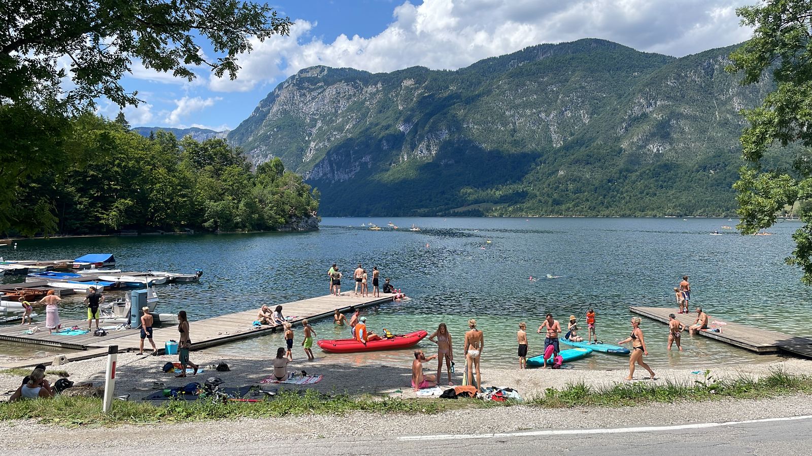 Het Bohinjmeer bij Ribčev Laz: steigers, zwemmers en suppers, met de bergen erachter